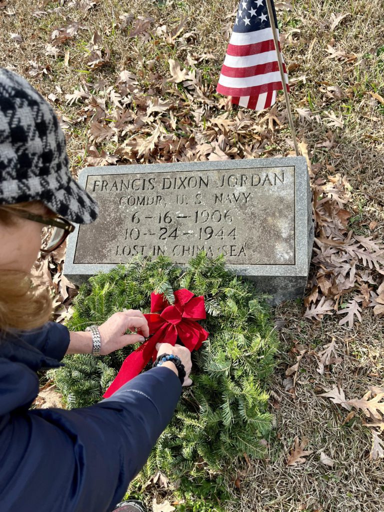 a woman placing a wreath on a grave