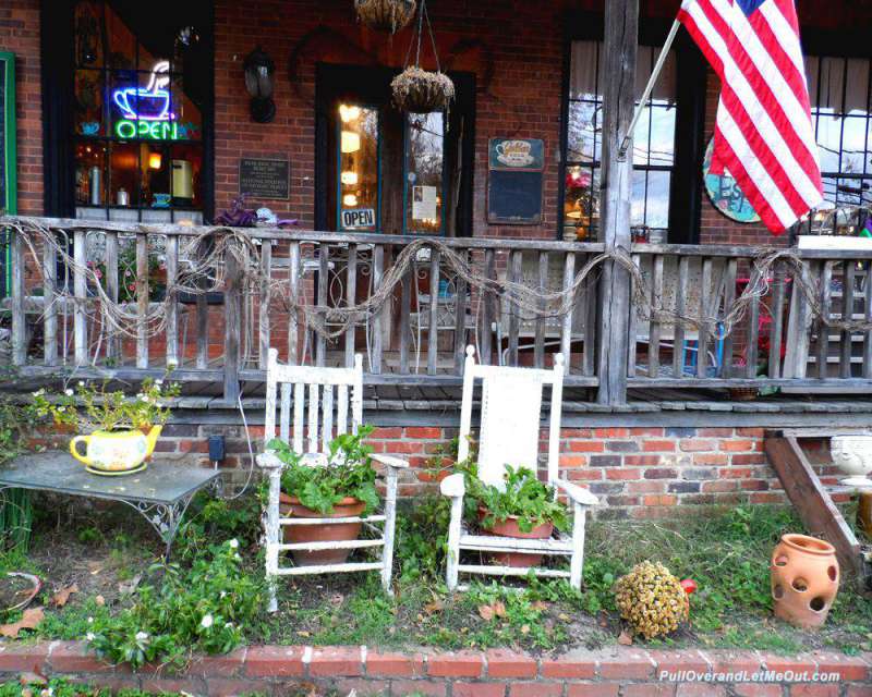 two white wooden rocking chairs in front of a store