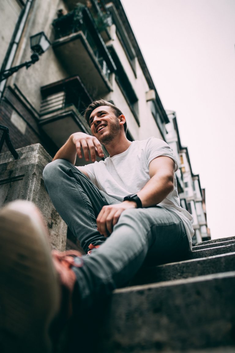 Man in jeans sitting on a step.