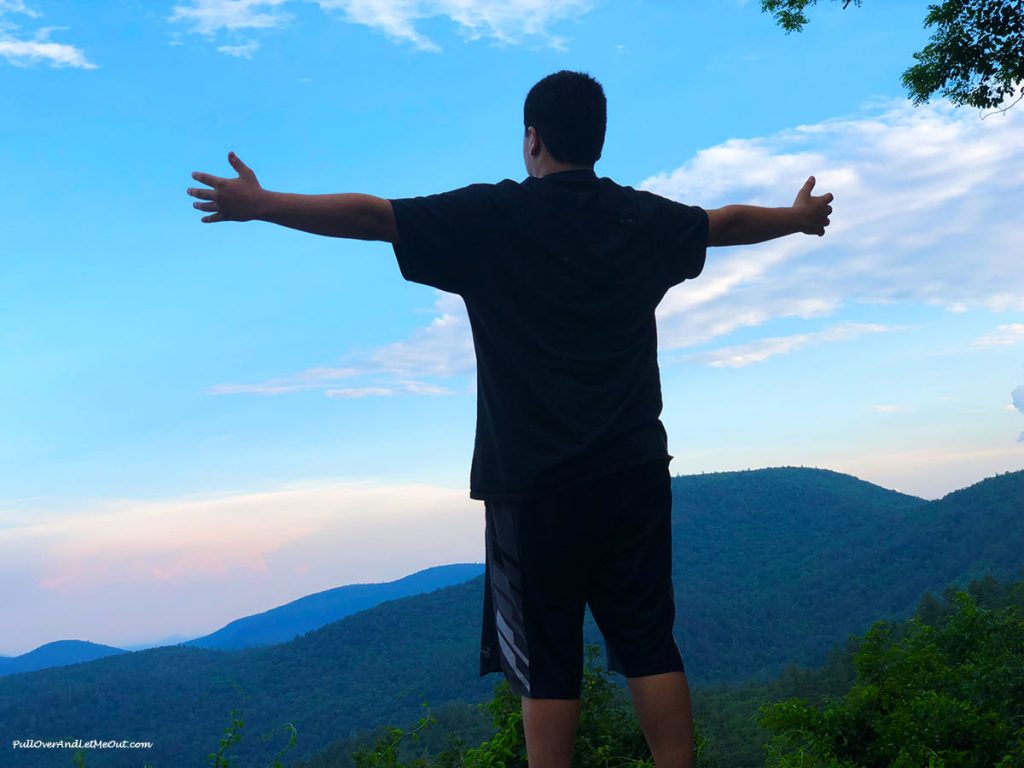 Guy with arms spread looking at mountains