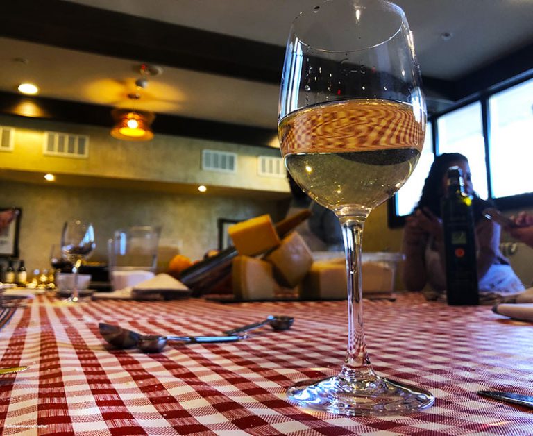 Glass of white wine on red and white checkerd table cloth at Il Palio Chapel Hill. PullOverAndLetMeOut