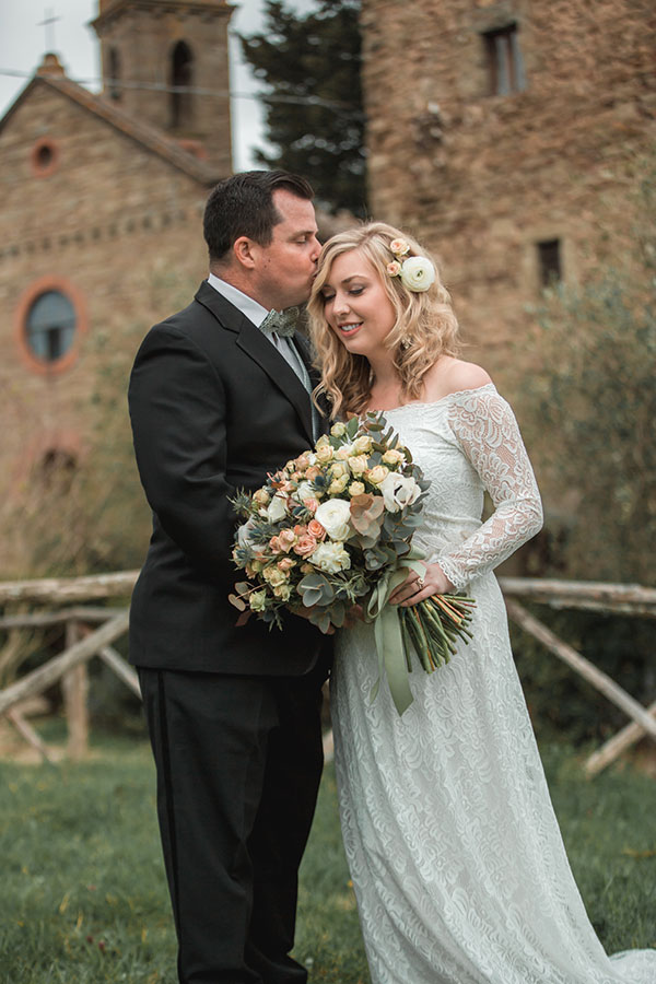 A bride and groom in front of a Tuscan castle