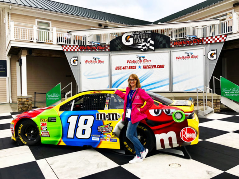 Woman standing in front of NASCAR number 18 M&M car