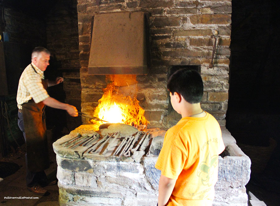 A boy watching a blacksmith working at Bunratty Castle and Folk Park