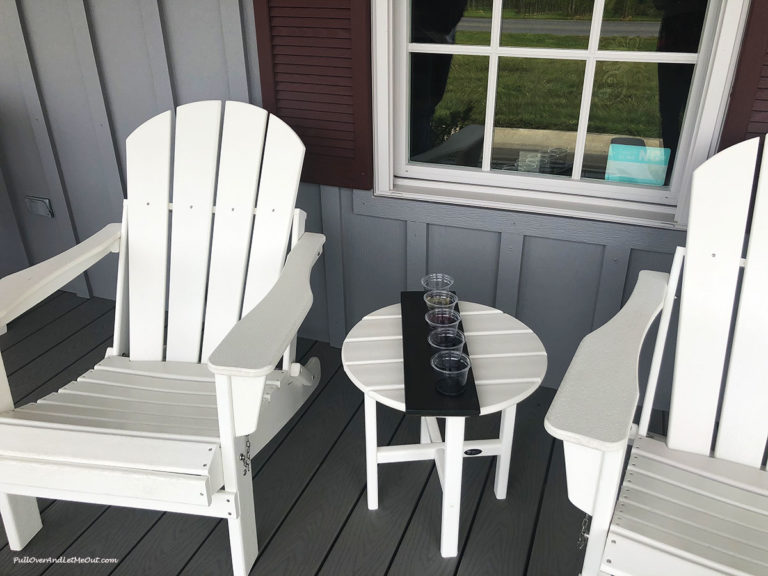 Chairs and table with a flight of wine sampels on a porch.