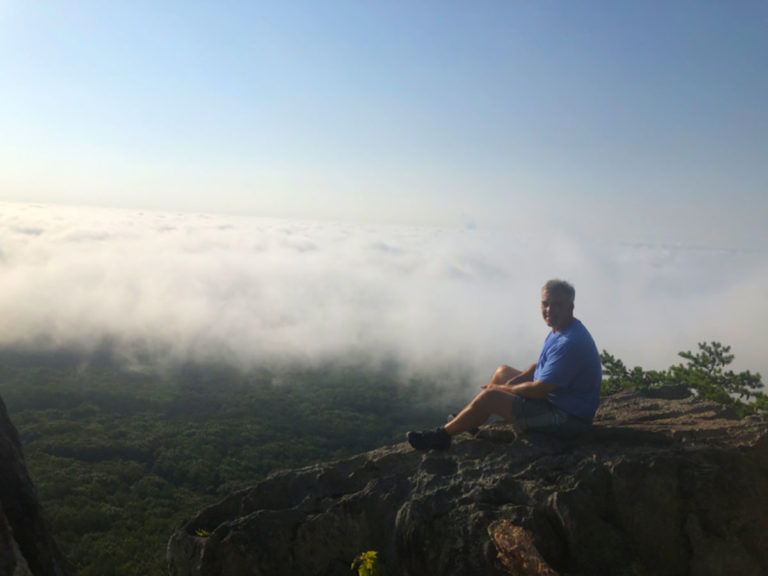 Man sitting on a mountain top at sunset