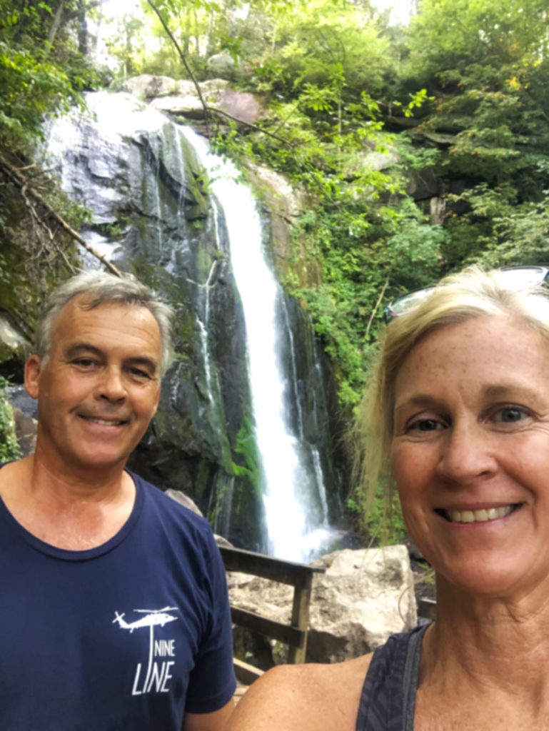 man and a woman standing in front of a waterfall