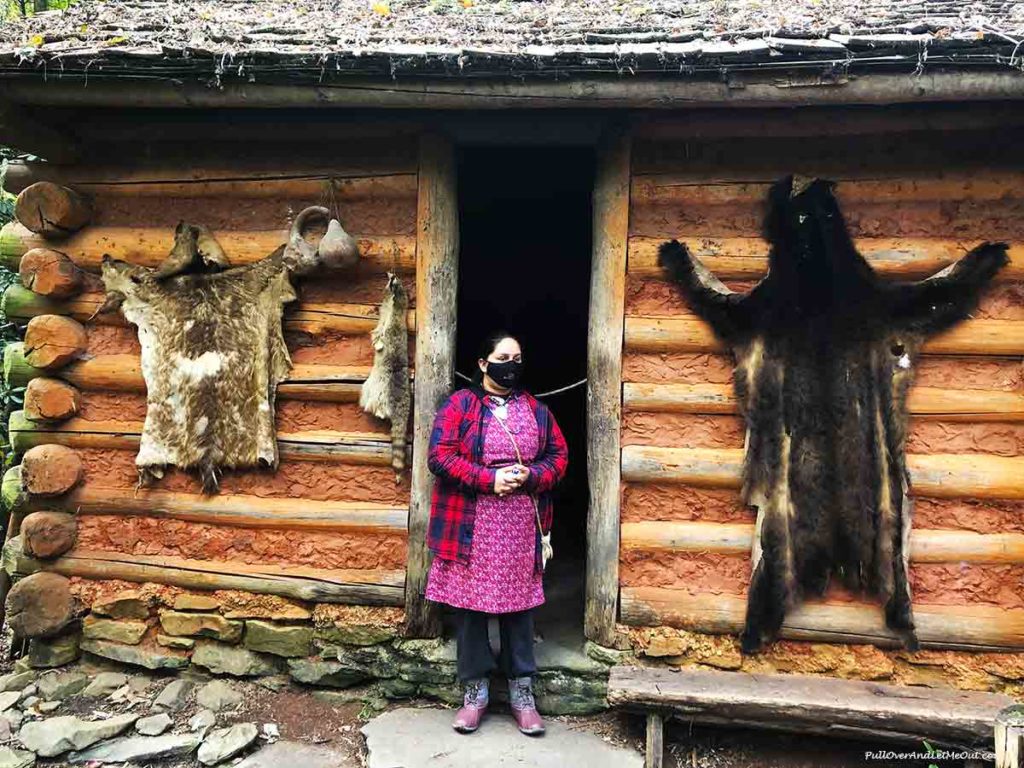 Cherokee tour guide in front of log cabin in Oconaluftee Indian Village Cherokee, NC