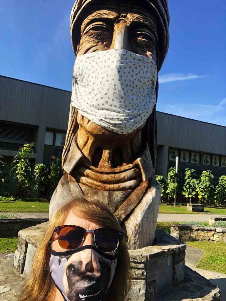 Woman in front of a large masked Native American wood sculpture in Cherokee, NC