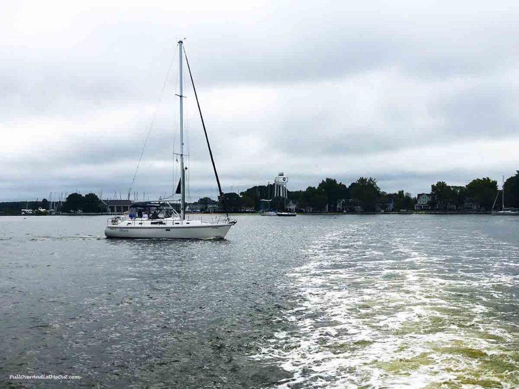 view of a sail boat on a river with the boat wake on the water