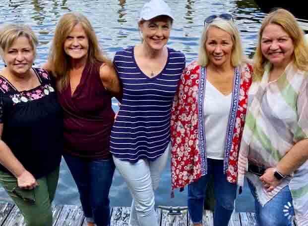 a group of women posing on a dock