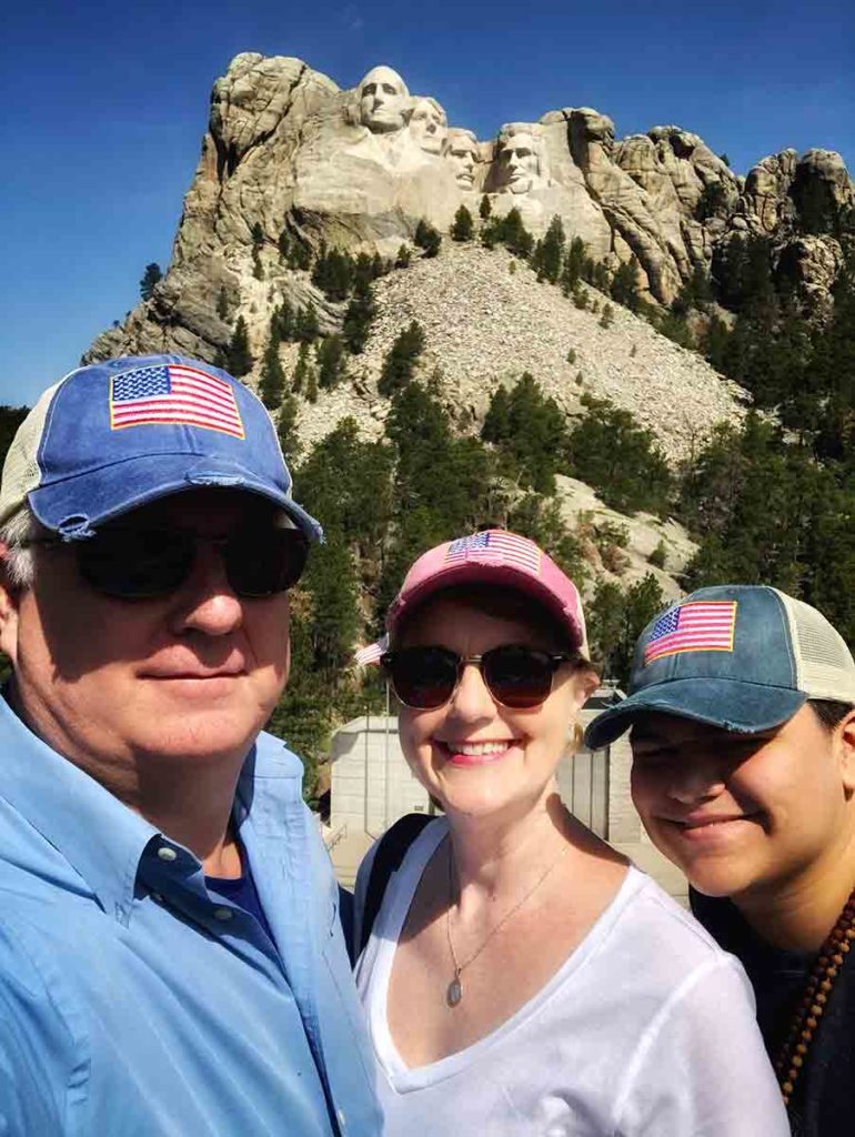 a family of 3 posing in front of Mount Rushmore