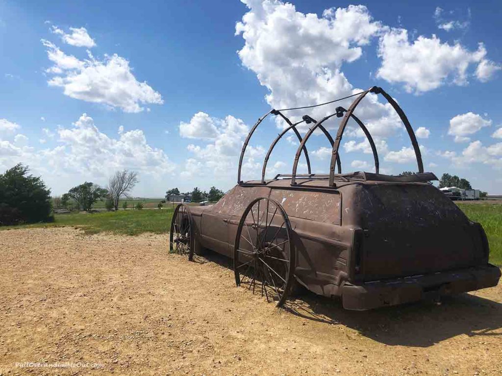 A scupture of a covered wagon made from an old station wagon