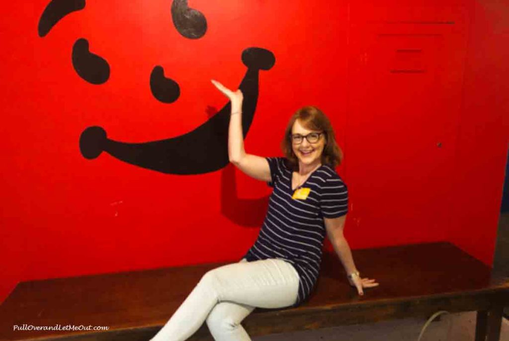woman sitting in front of a wall picture of the Kool-Aid Man