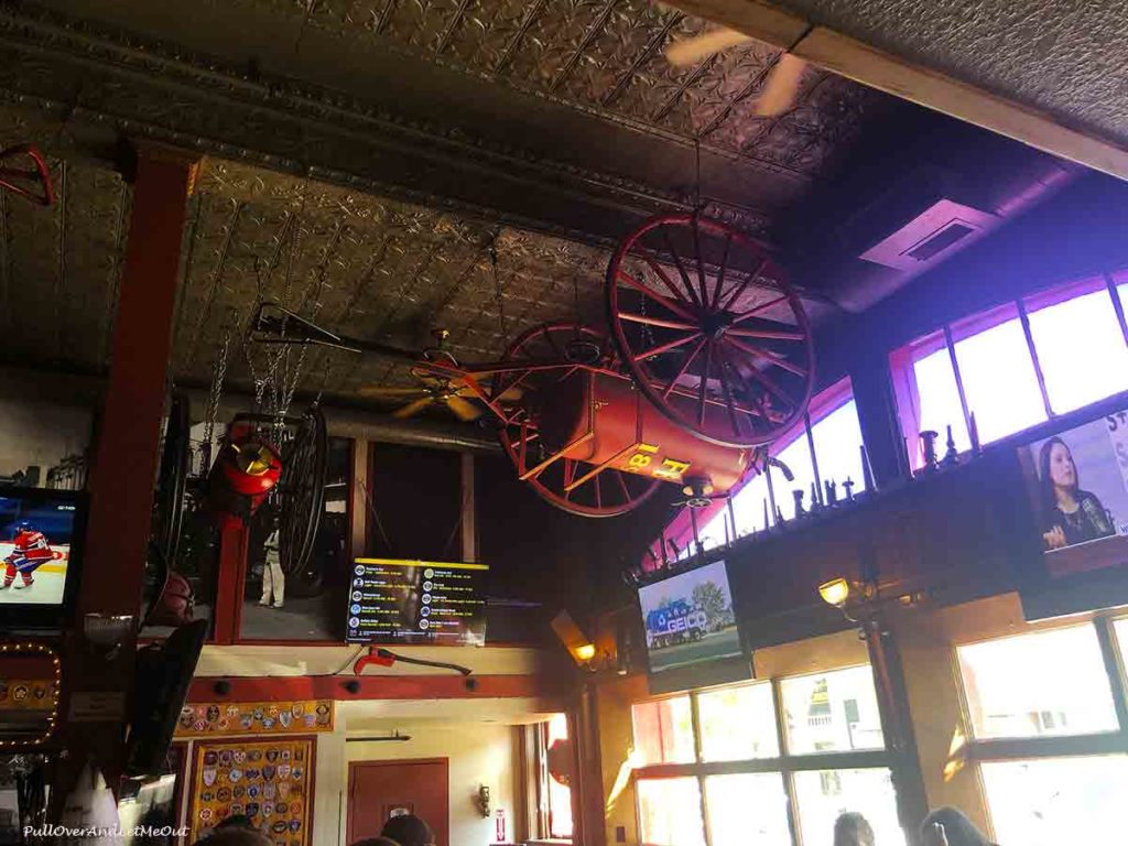 old fire engine hanging on the ceiling of a fire house