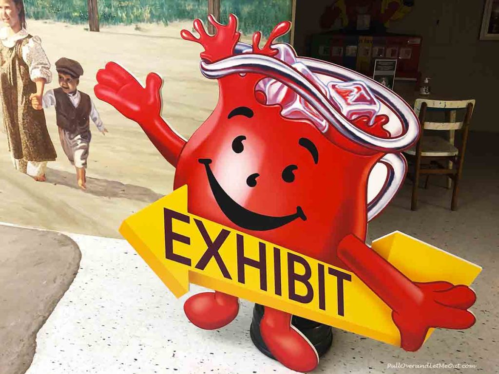 The Kool-Aid Man sign holding an arrow that says "exhibit"