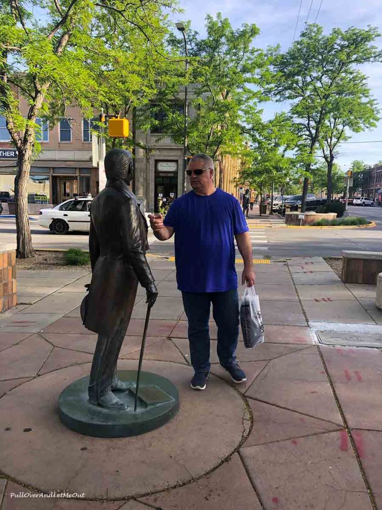 man looking at a bronze statue of John Quincy Adams