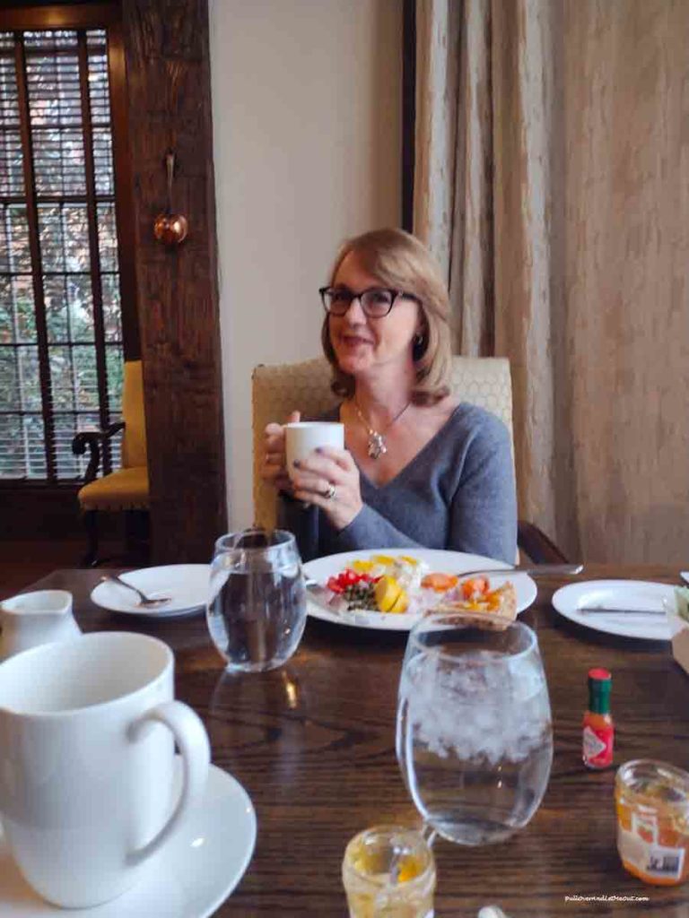 woman sitting at a breakrfast table with a cup of coffee