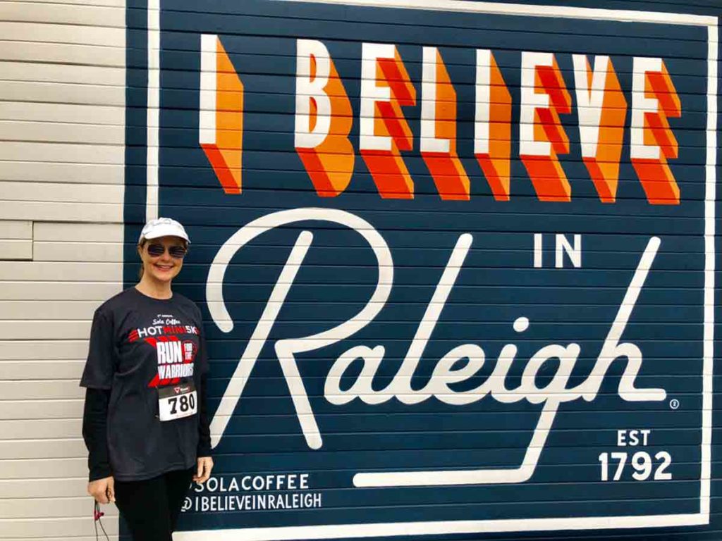 woman after running a 5K in front of a sign