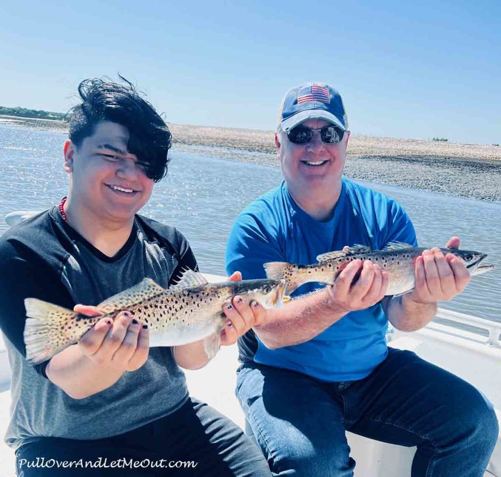 Two men on a fishing boat holding fish