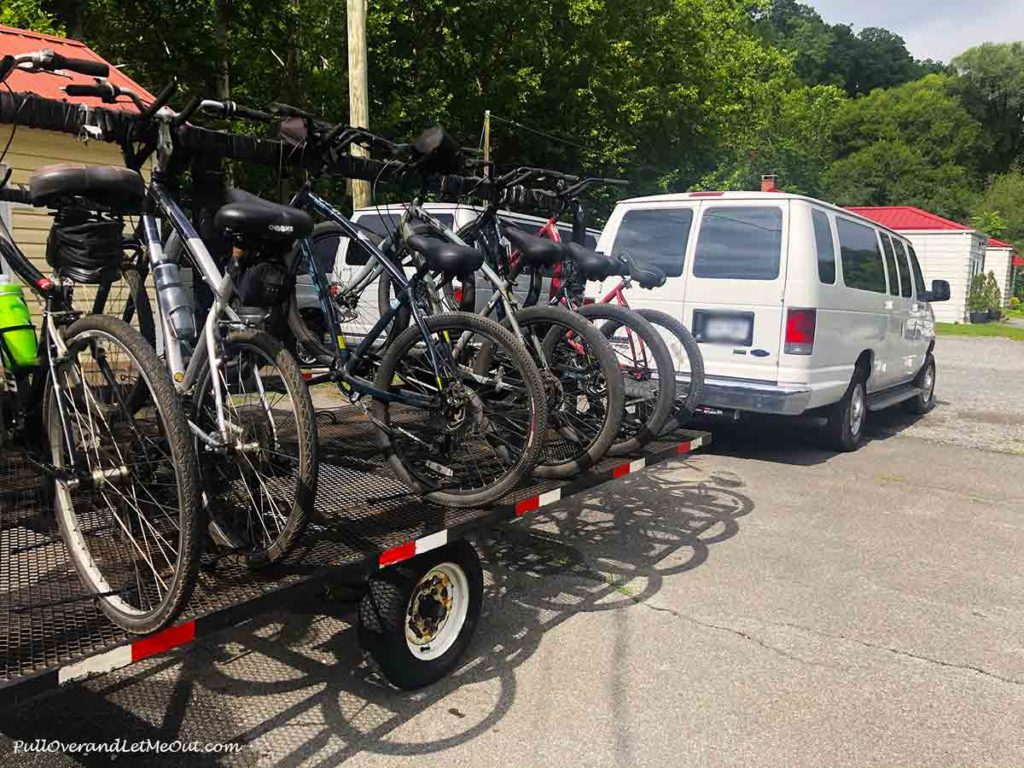 A white van with a trailer attached that's full of bicycles