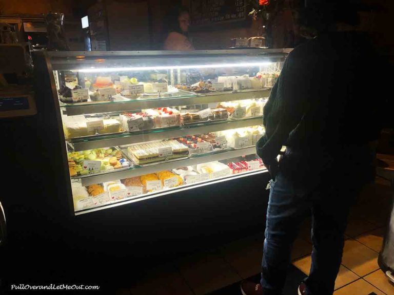 a woman looking at a bakery glass case
