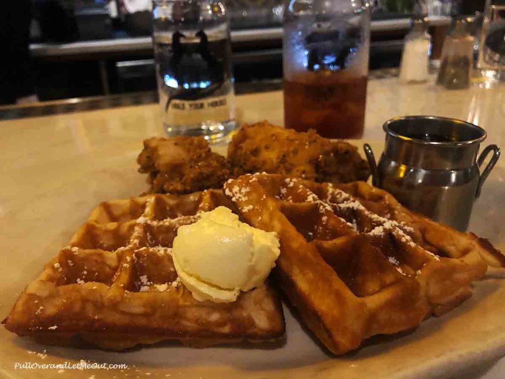 chicken and waffles on a plate with a big dollop of butter on the waffle