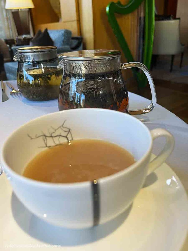 a cup of tea in front of tea pots