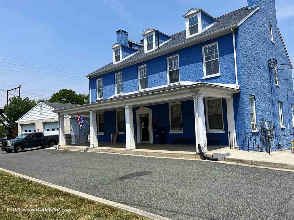 a historic blue building with a porch.