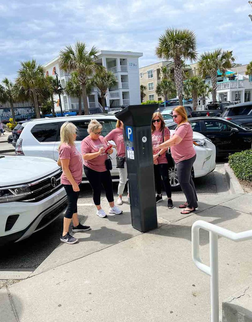five women figuring out how to use a parking meter