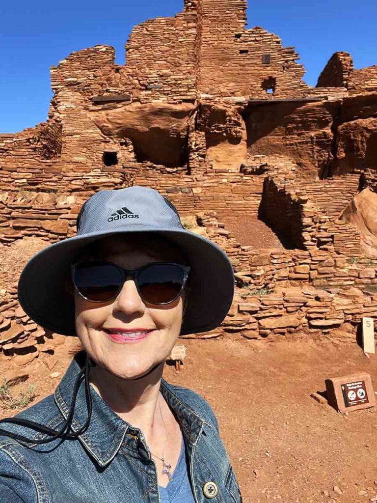 a woman standing in front of a Hopi pueblo