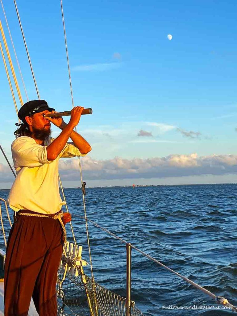 a sailor on a sailboat looking through a telescope