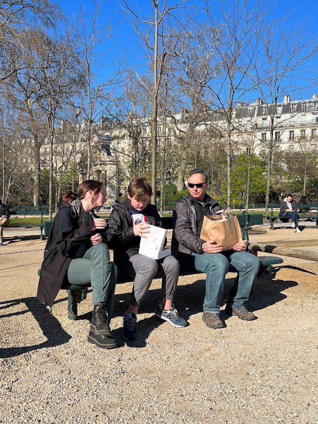people on a bench in Paris eating macarons.