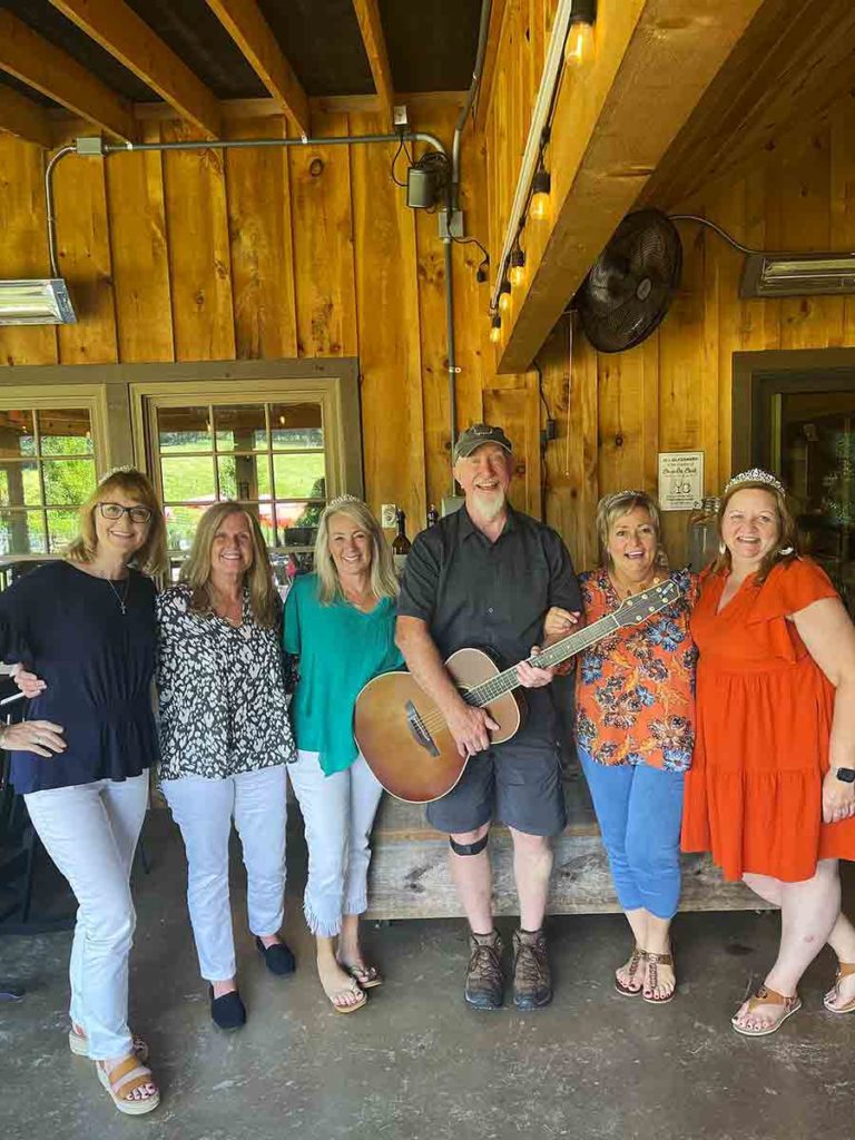 a group of ladies standing aroudn a man with a guitar