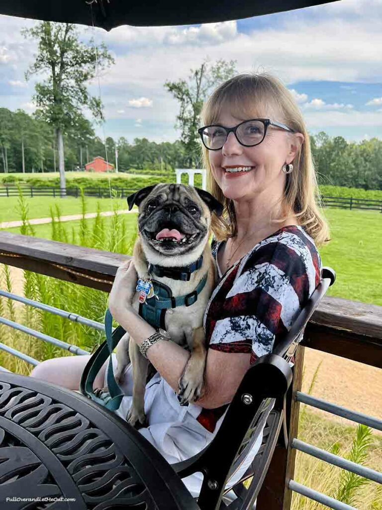 a woman holding a pug at a winery