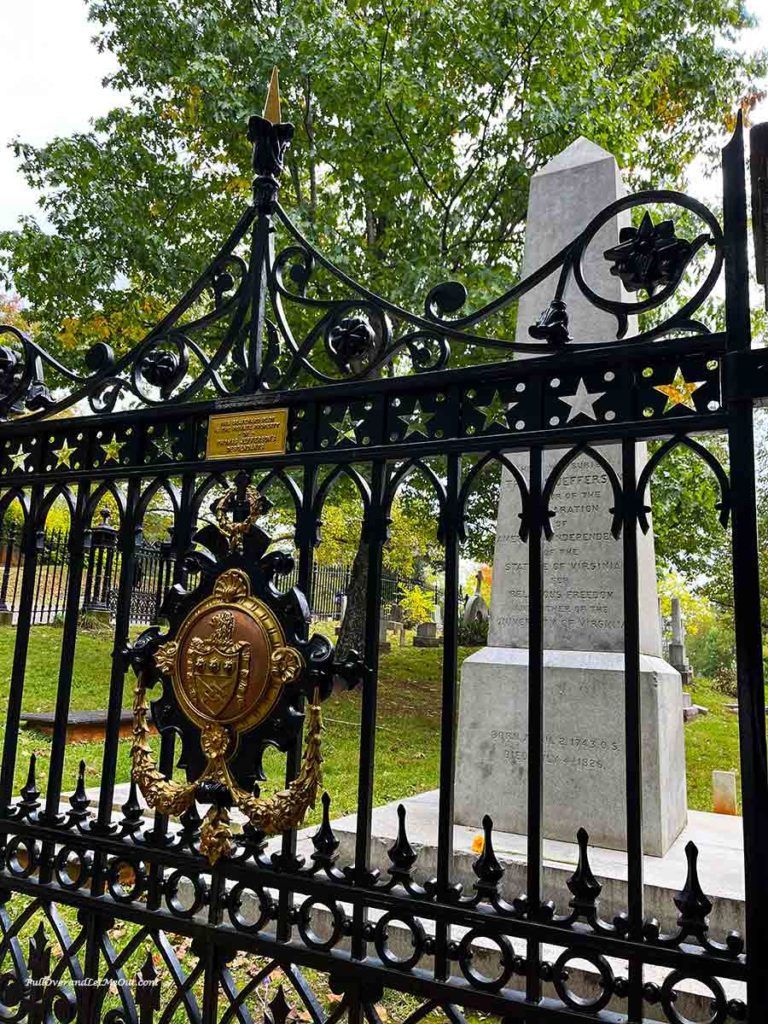 Thomas Jefferson's grave behind a black gate with a coat of arms on it.