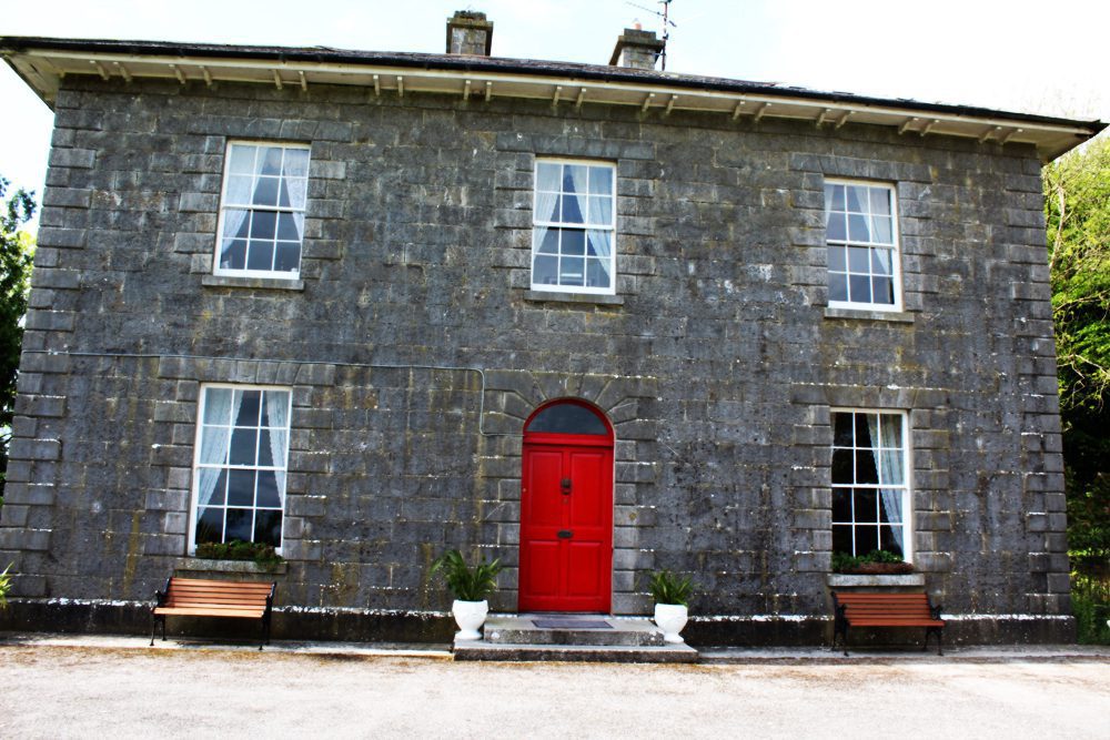 A Georgian home made of stone with a red door.