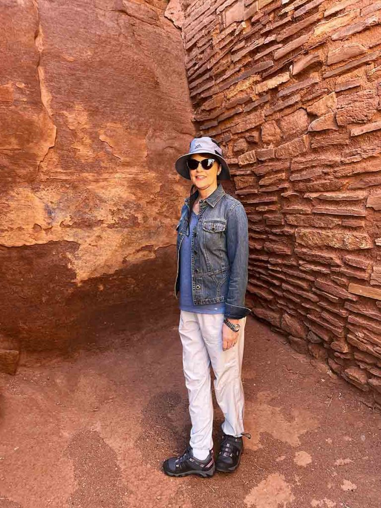 a woman standing inside an ancient Hopi dwelling