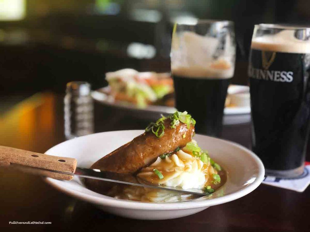 a plate of bangers and mash in front of a couple of pints of Guinness
