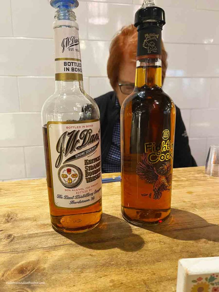 two bottles of bourbon in front of a woman