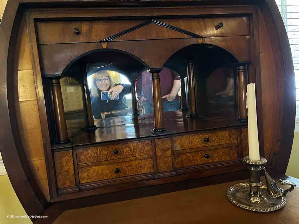 a woman's reflection in a mirror on a piece of furniture