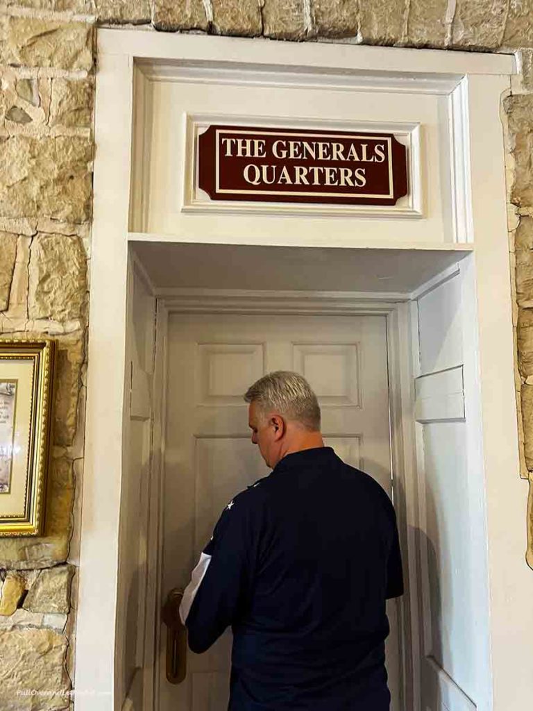a man opening a door that has a sign over it that says "General's Quarters."