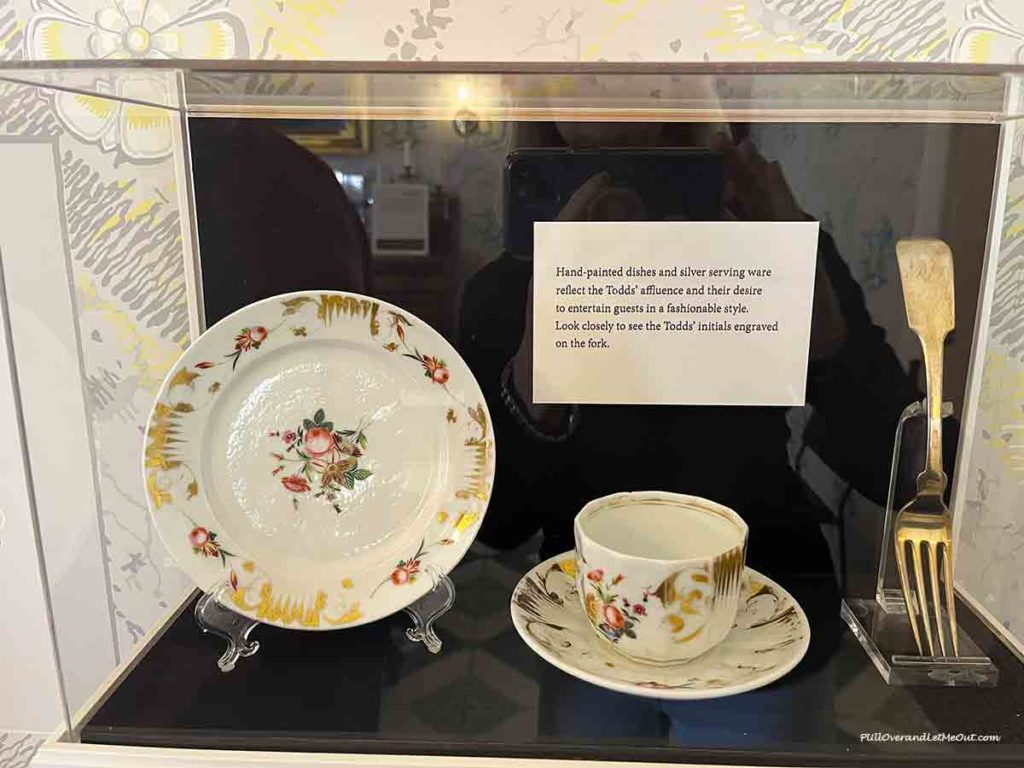 a plate, cup and saucer, and a silver fork in a display case.