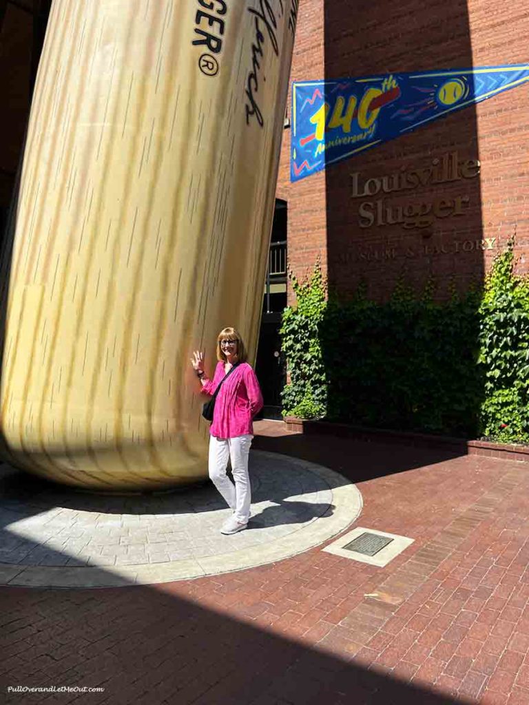 a woman standing next to a giant baseball bat.