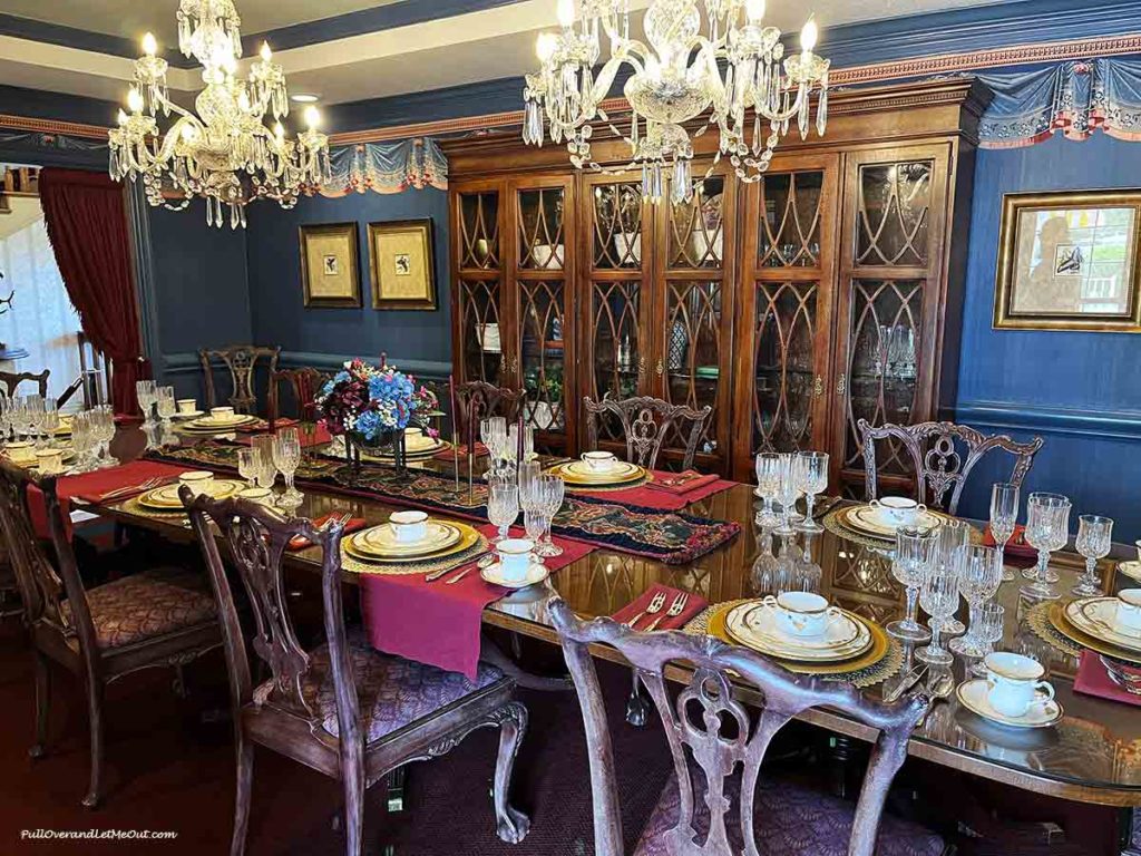 a long dining room table fully set with dishes and glasses.