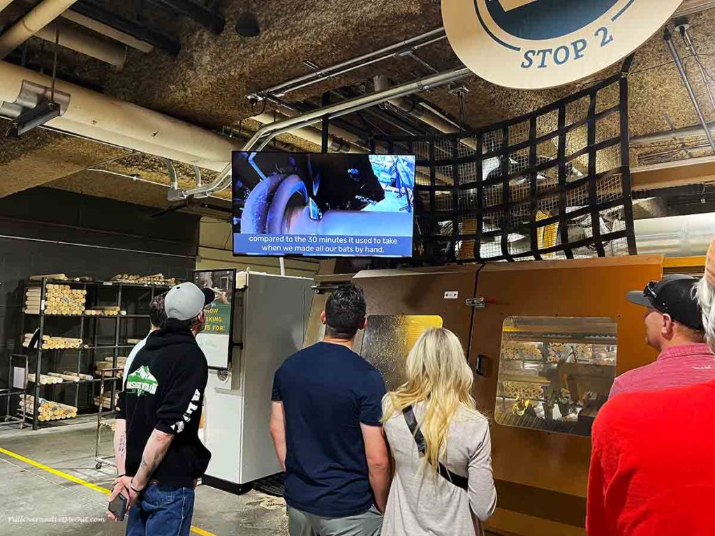 people taking a tour of a baseball bat factory