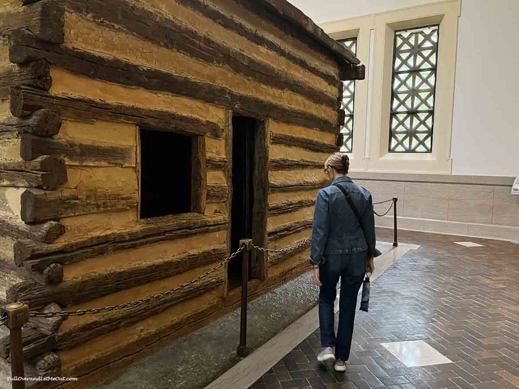 a woman looking at a log cabin