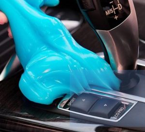 blue car cleaning gel being used to clean a car console