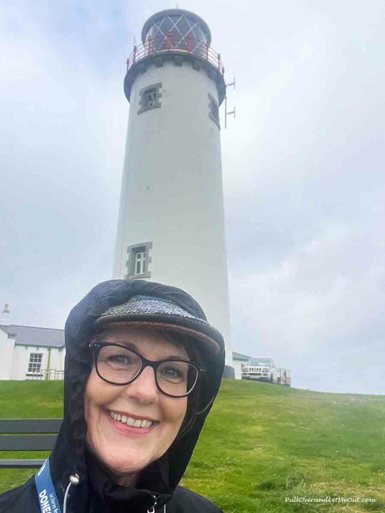 a woman standing in front of a lighthouse