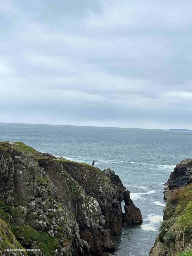 a man standing on rocks above the coast below